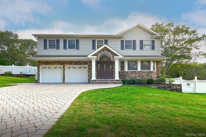 View of front of house featuring stone siding, decorative driveway, and a garage