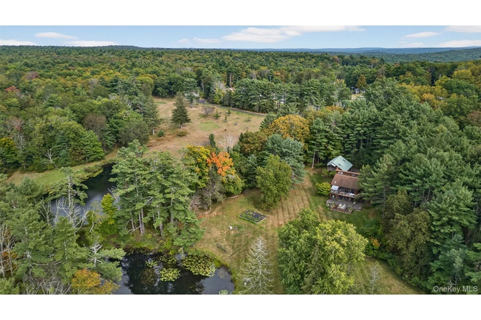 Aerial view of property and surrounding area with a large body of water and a heavily wooded area