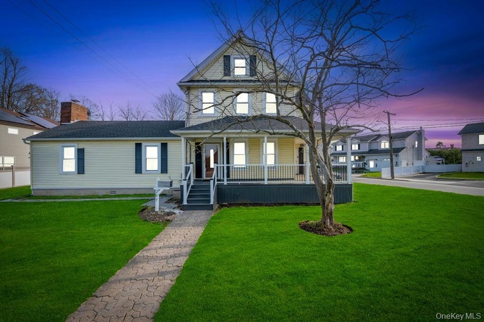 Traditional style home featuring covered porch and a front yard