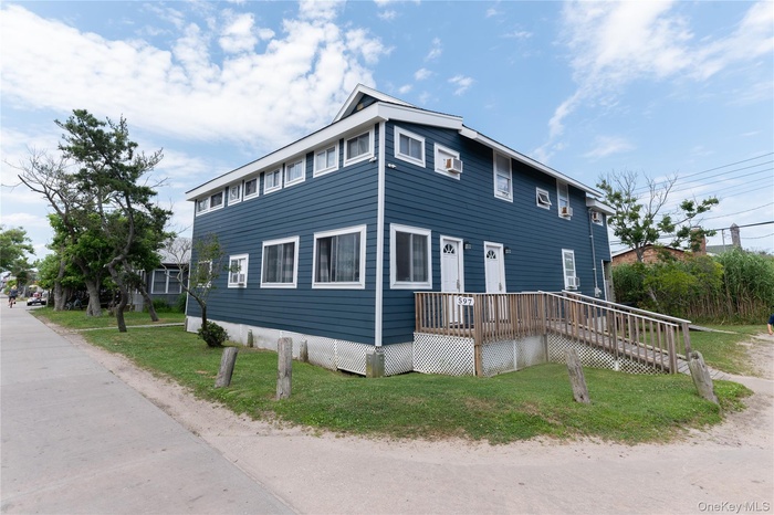 View of front of property featuring a front lawn and a wooden deck