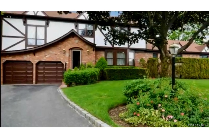 Tudor-style house featuring asphalt driveway, a garage, and a front lawn