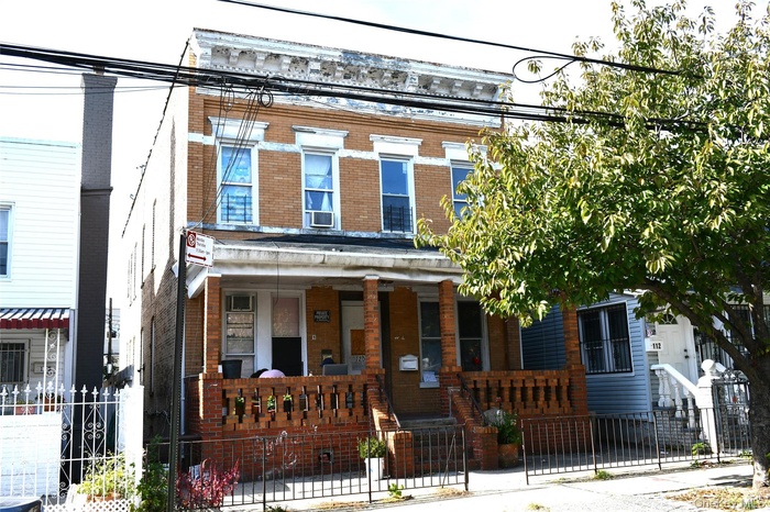 View of front of property featuring brick siding, a fenced front yard, a porch, and a gate