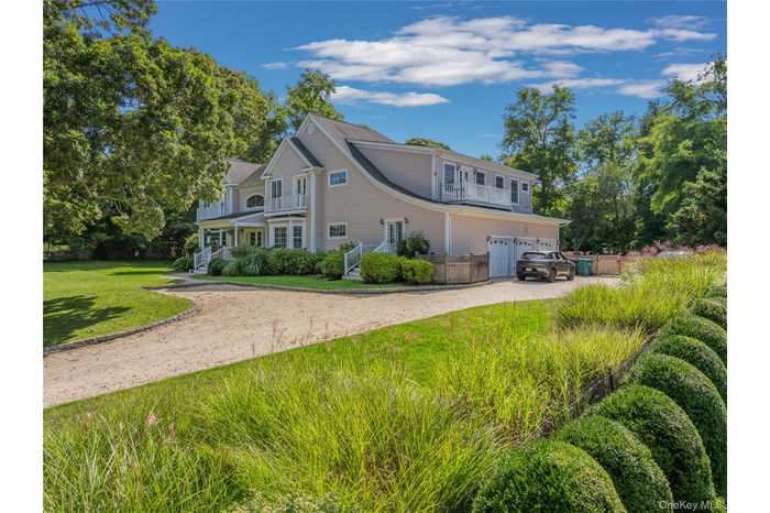 View of front of home featuring driveway, a front lawn, an attached garage, and covered porch