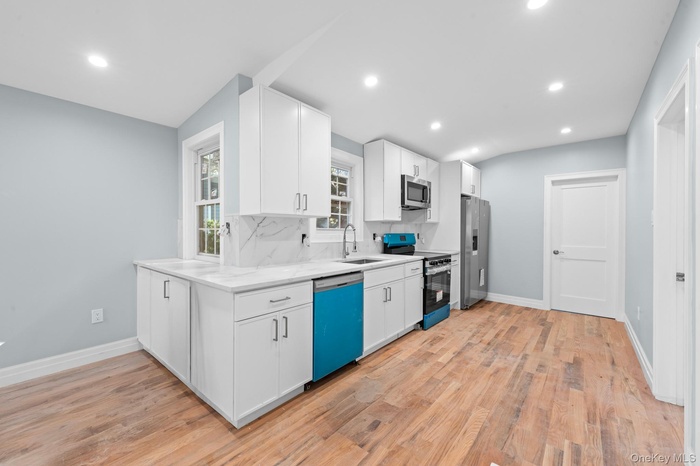 Kitchen featuring appliances with stainless steel finishes, recessed lighting, white cabinets, light wood-style floors, and tasteful backsplash