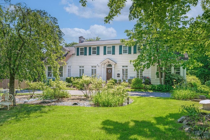 Colonial house with circular driveway and expansive front yard.