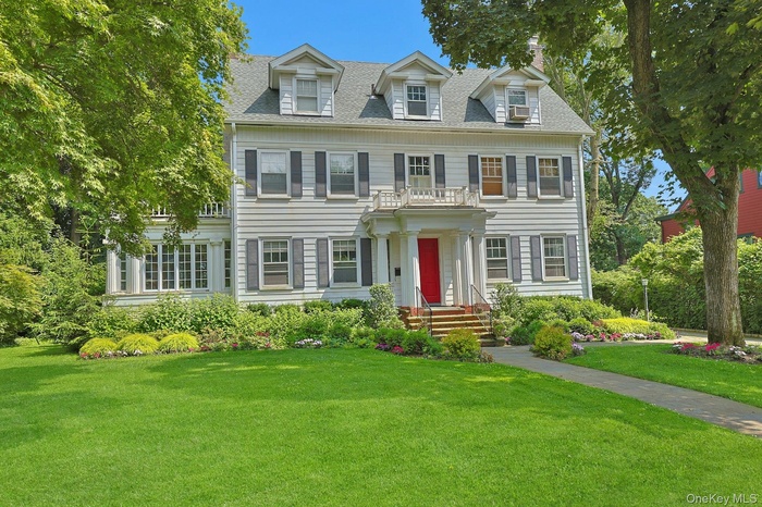 Colonial house featuring a front lawn and roof with shingles