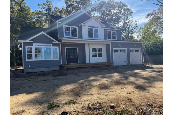 View of front of house featuring driveway, covered porch, and an attached garage