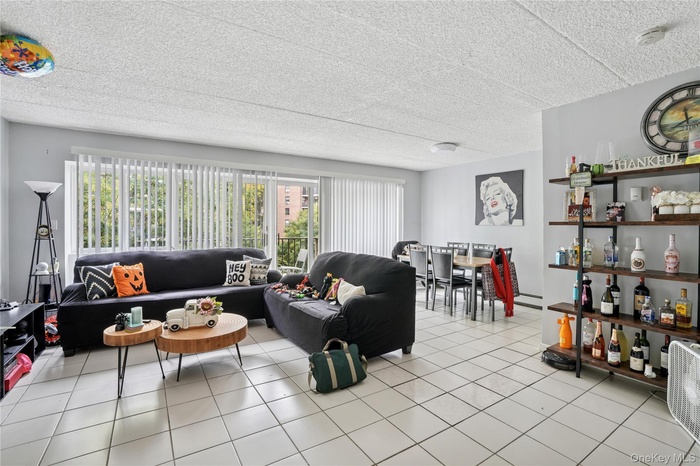 Living area featuring light tile patterned floors, a textured ceiling, and baseboard heating