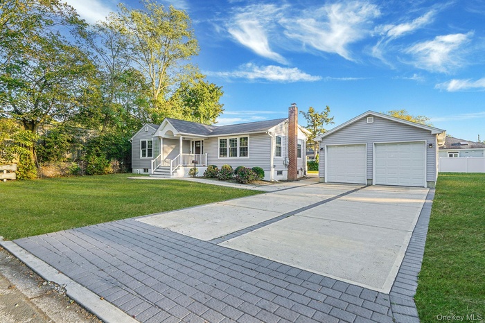 Ranch-style home featuring a front yard, an outbuilding, a porch, and a garage