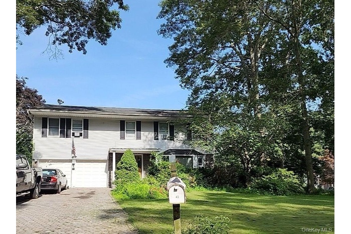 View of front of property featuring a front lawn, driveway, and a garage