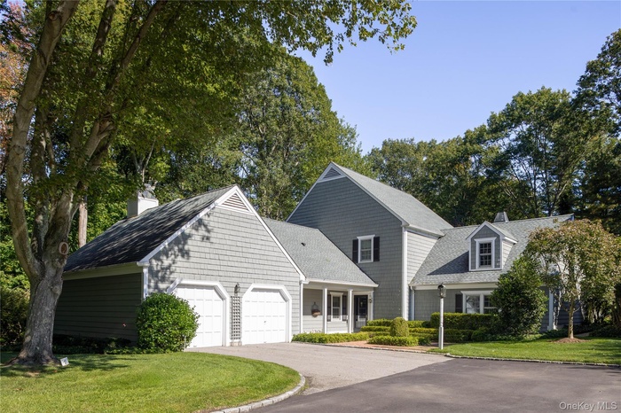 View of front of home with a chimney, driveway, a garage, and a front lawn