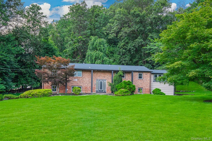 Bi-level home featuring a front lawn and brick siding