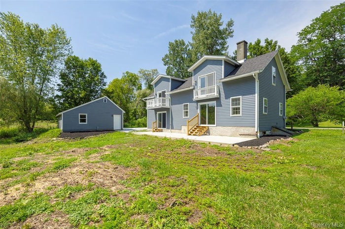 Back of house with a patio, an outbuilding, and a yard