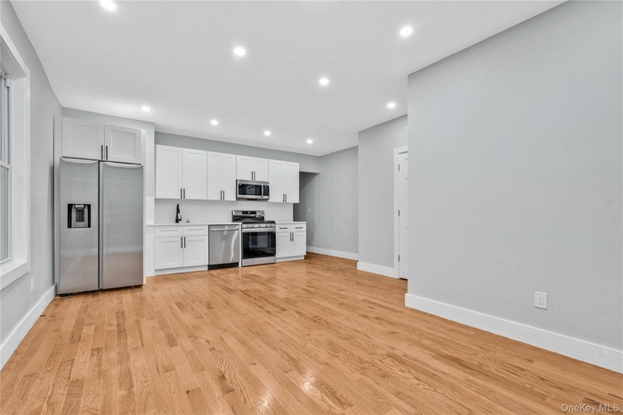 Kitchen featuring white cabinets, appliances with stainless steel finishes, light countertops, light wood finished floors, and recessed lighting