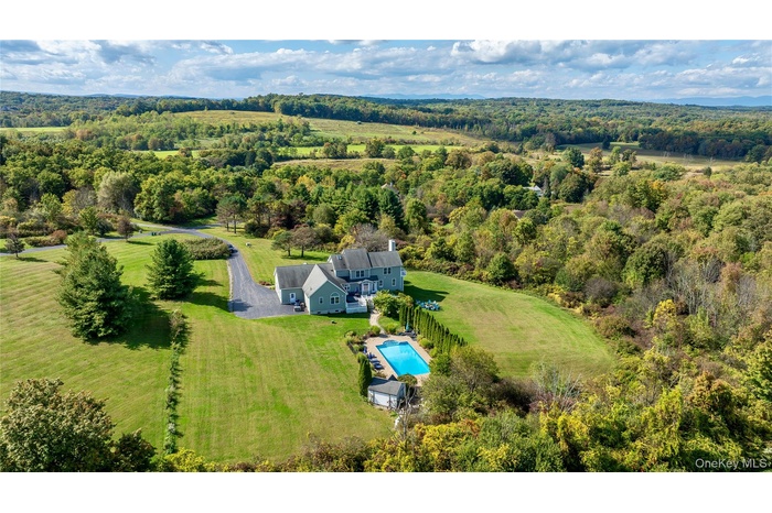 View of subject property featuring a pool and a forest