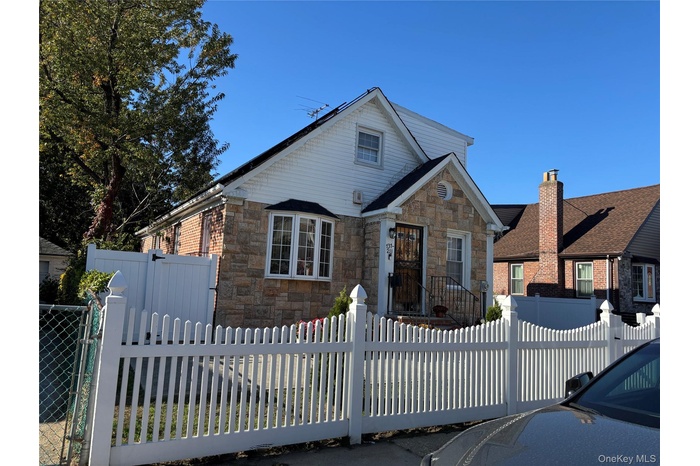 View of front of house featuring a fenced front yard, stone siding, and a gate