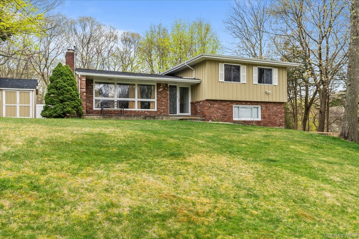 Tri-level home featuring brick siding, a chimney, and a front lawn