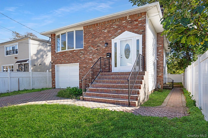 View of front of property featuring decorative driveway, brick siding, and a garage