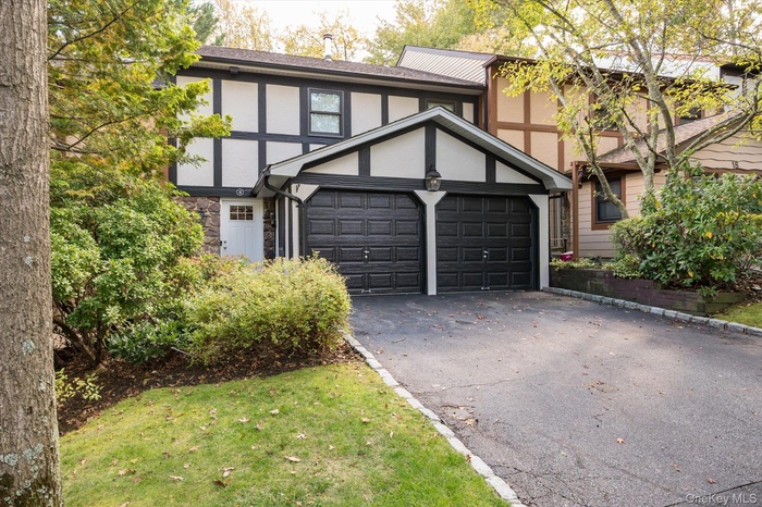 Tudor home with stucco siding, driveway, and stone siding