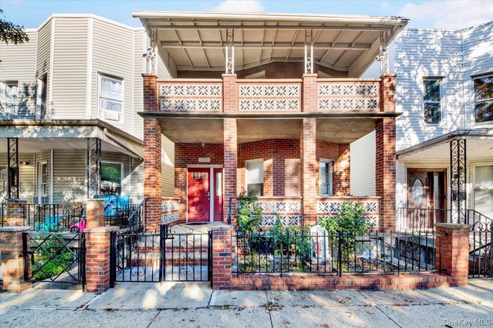 View of front of house with a gate, brick siding, a fenced front yard, and covered porch