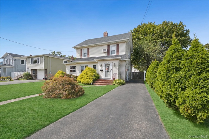 View of front of property with a chimney and driveway
