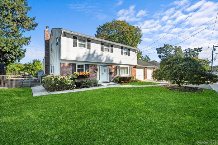 Colonial home featuring brick siding, a chimney, a garage, and driveway