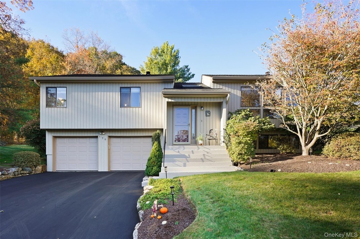 View of front of property with asphalt driveway, a front lawn, and a garage
