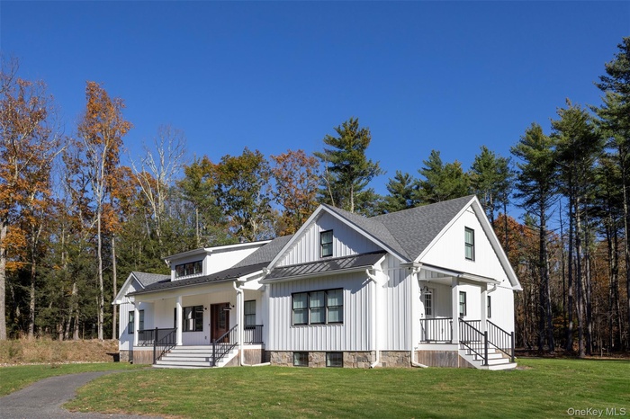 Contemporary farmhouse style home with a porch, a standing seam roof, a front yard, and a shingled roof