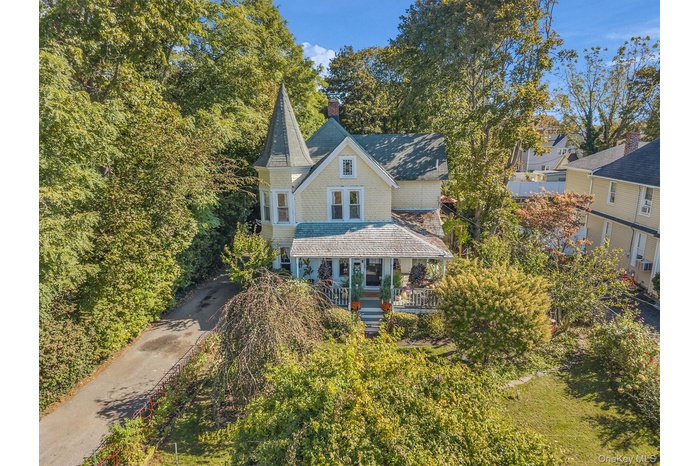 View of front of home with a porch, a chimney, and driveway