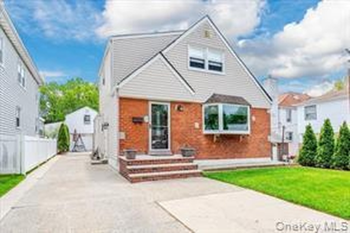View of front facade with concrete driveway and brick siding