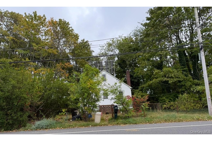 View of side of property with view of scattered trees and a chimney