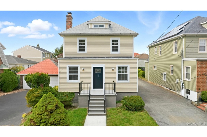 American foursquare style home with a chimney, driveway, and roof with shingles