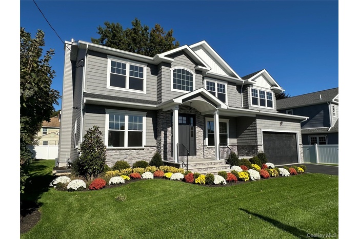 View of front of house with stone siding, a chimney, asphalt driveway, and a porch