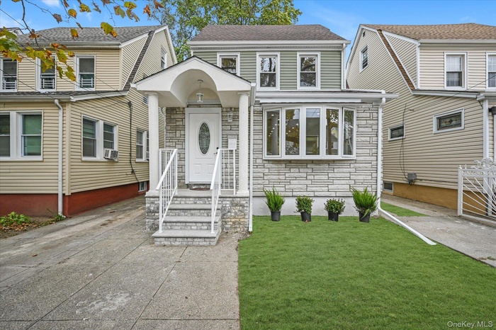 View of front of property featuring stone siding and a front yard