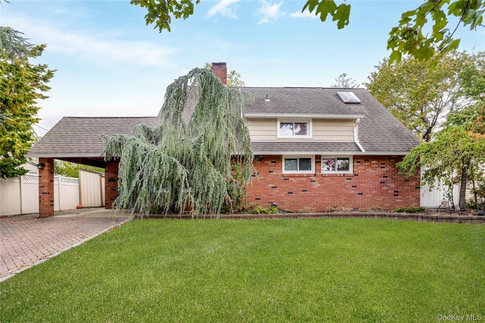 Back of house with a chimney, brick siding, and a shingled roof