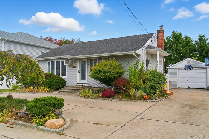 View of front facade with an outdoor structure, a chimney, a garage, and roof with shingles
