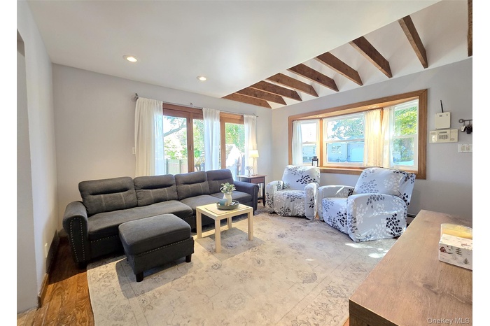 Living area with beamed ceiling, wood finished floors, and recessed lighting