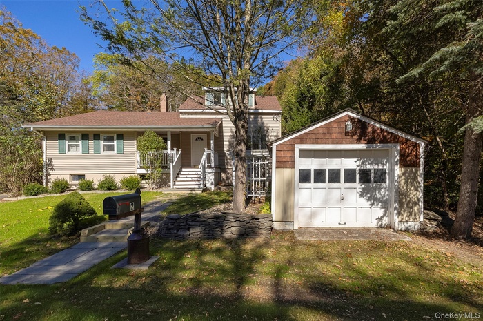 View of front of home featuring an outdoor structure, a front lawn, a detached garage, and a chimney