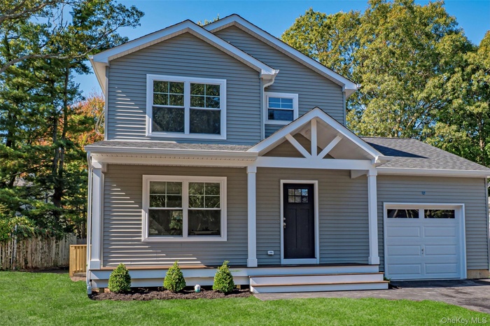 View of front facade featuring a garage, a shingled roof, covered porch, and driveway