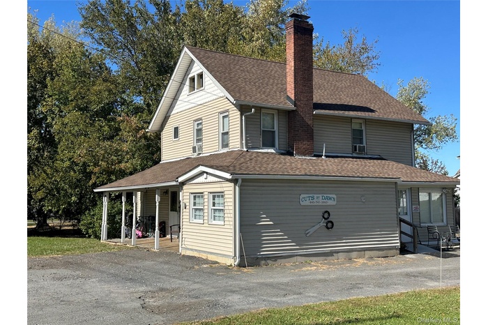 Farmhouse-style home featuring a shingled roof, a chimney, and driveway