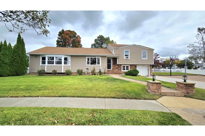 Tri-level home with an attached garage, concrete driveway, and a front yard