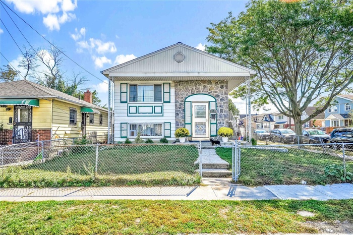 View of front of home with a fenced front yard and stone siding