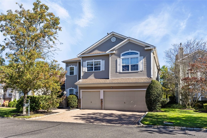 View of front of property featuring decorative driveway, an attached garage, a front yard, and a shingled roof
