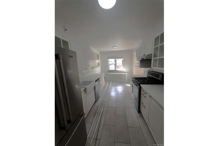 Kitchen featuring appliances with stainless steel finishes, white cabinets, and backsplash
