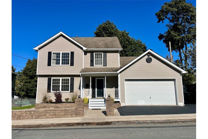 View of front of property with a porch, asphalt driveway, roof with shingles, and an attached garage