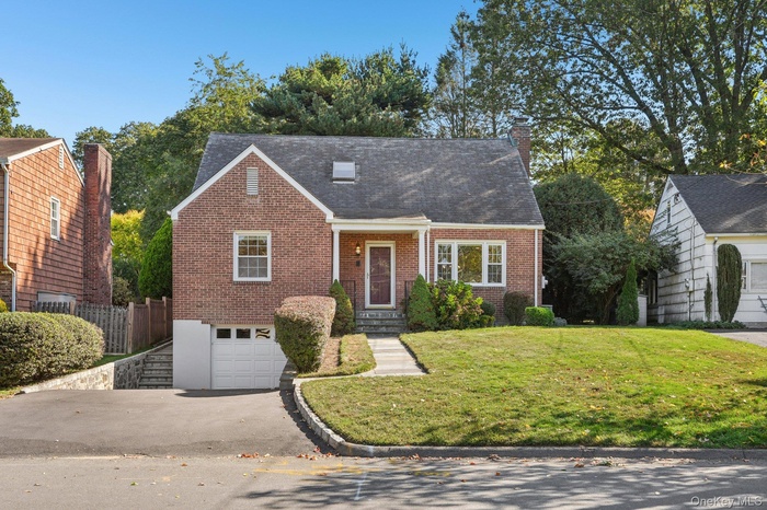 View of front of home with brick siding, asphalt driveway, a garage, a porch, and roof with shingles