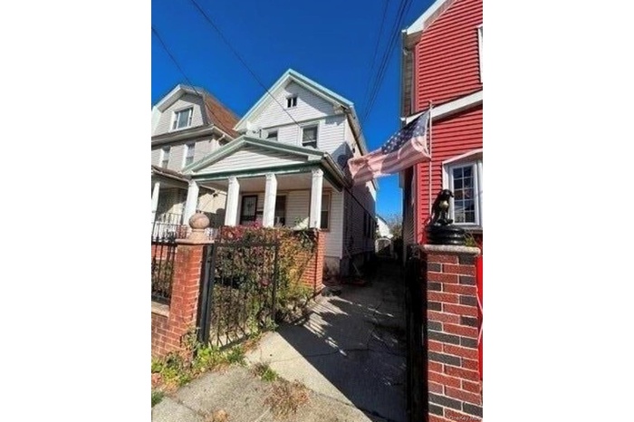 View of side of home featuring a gate and covered porch