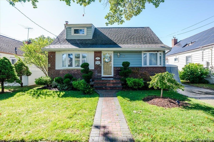 Bungalow-style house featuring brick siding, a front yard, and roof with shingles