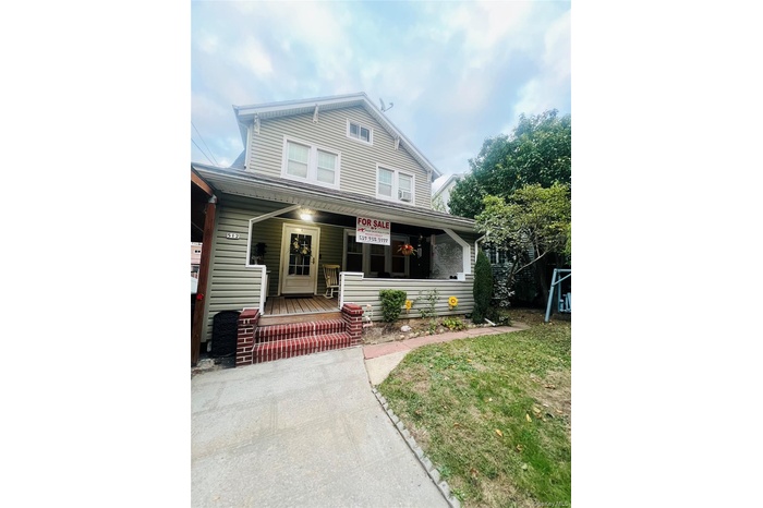 View of front of house with covered porch and a front lawn