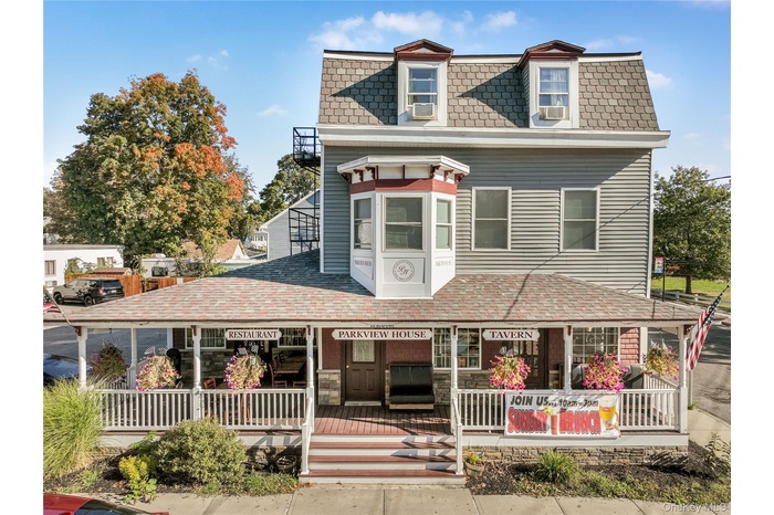 Second empire-style home with mansard roof, a porch, and roof with shingles